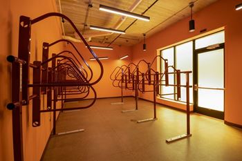 A gym with orange walls and a row of exercise equipment.